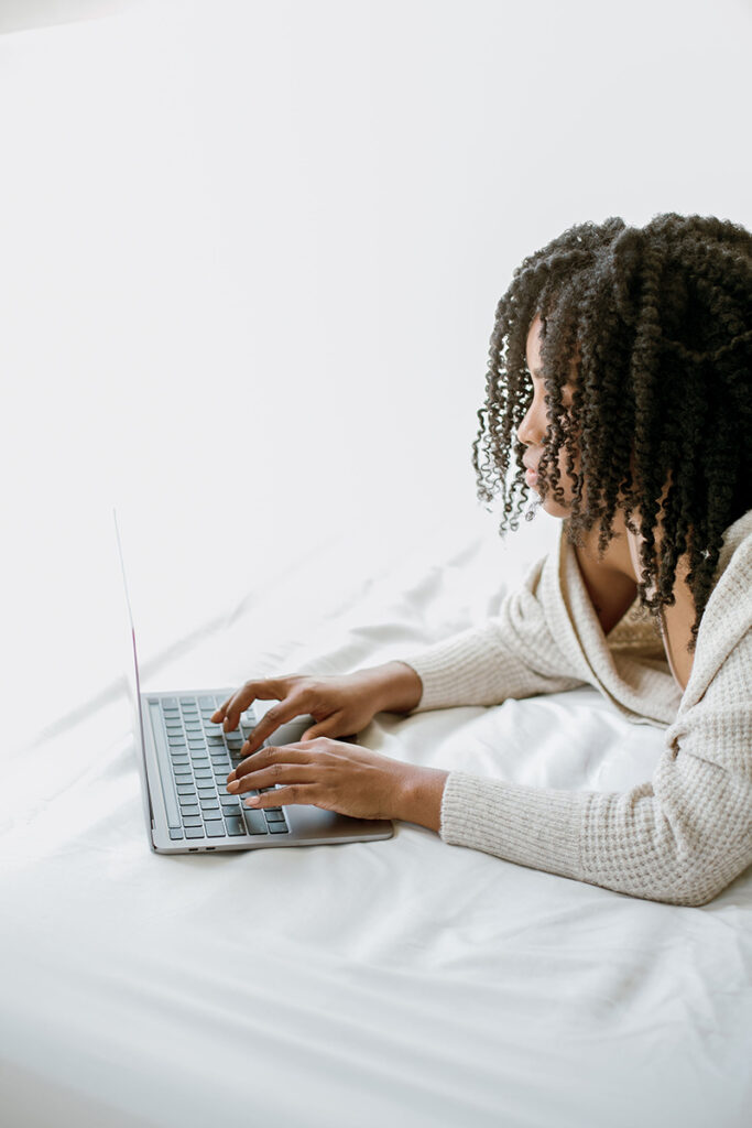 Woman lying in bed working on laptop computer